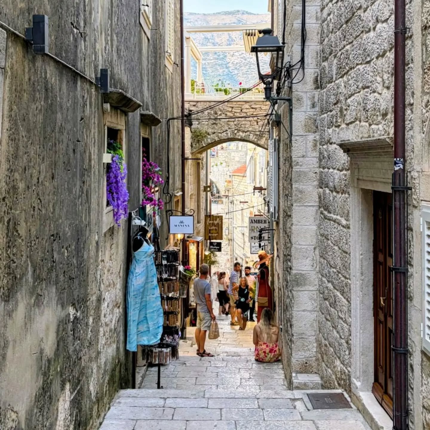 A narrow stone alley in Korčula old town with shops and visitors