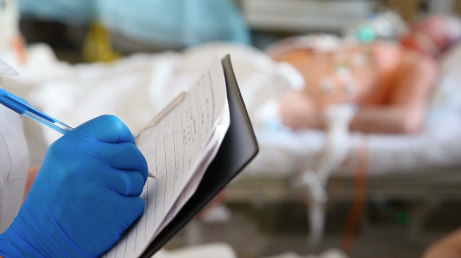 Medical professional taking notes beside a hospital patient